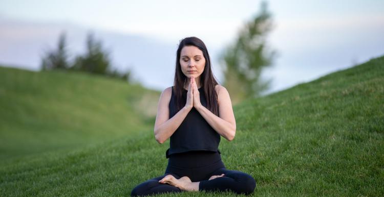 person sitting in meditation in green grass person sitting in meditation in green grass