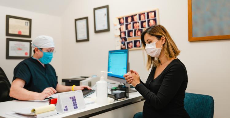 woman with face mask at the reception of doctors office woman with face mask at the reception of doctors office