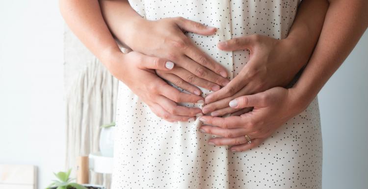 pregnant woman with partner hugging from behind pregnant woman with partner hugging from behind