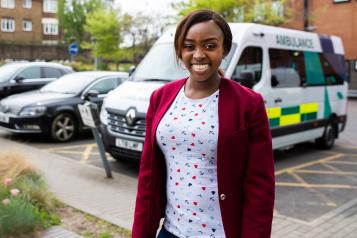 smiling woman standing in front of ambulance