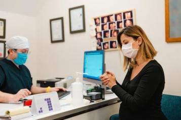 woman with face mask at the reception of doctors office