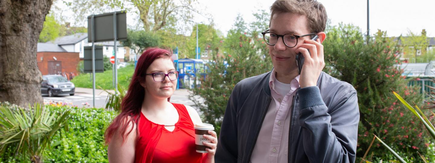 Man on the phone outside, standing next to a woman